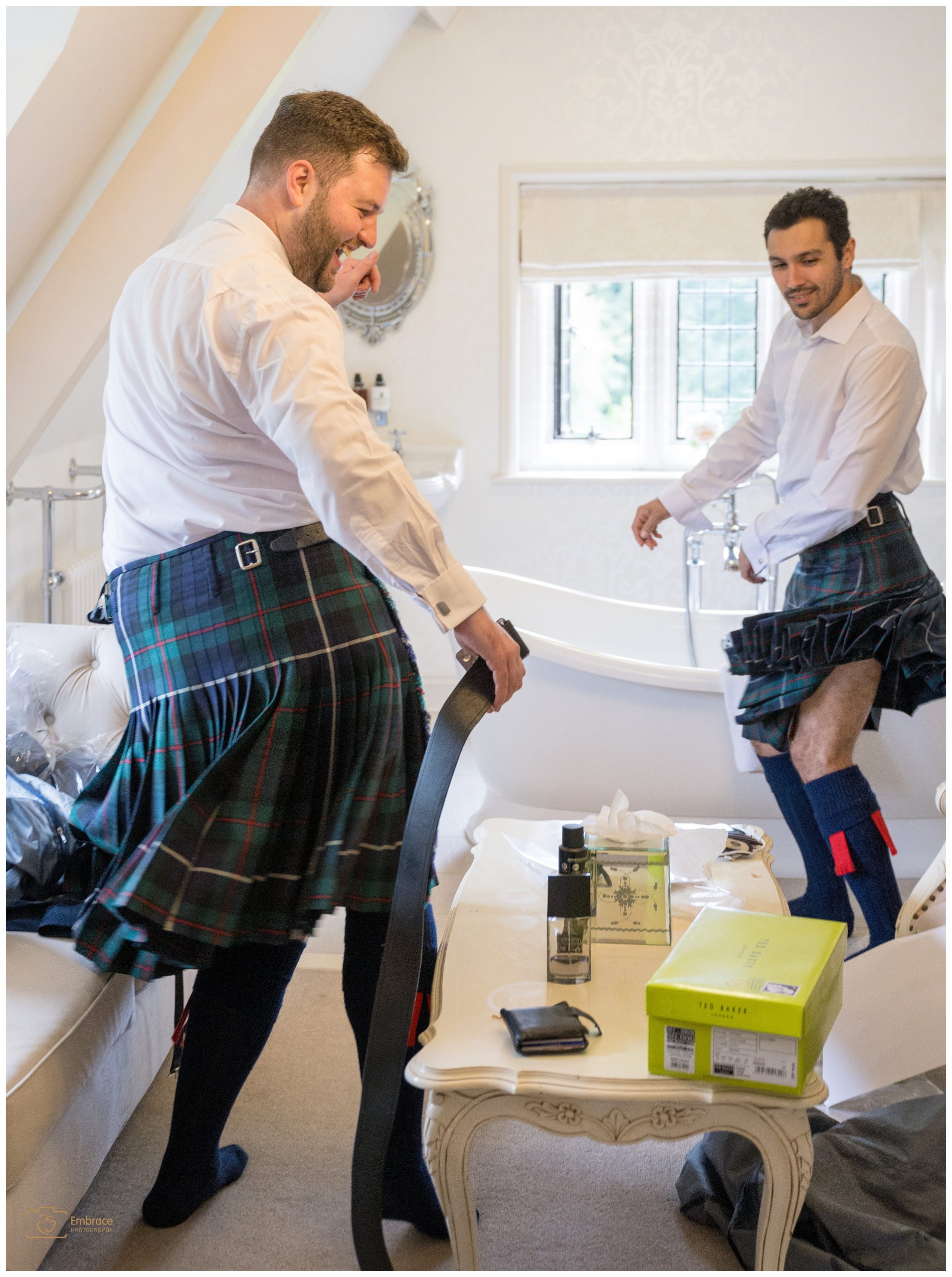 Two groomsmen having fun in their kilts whilst getting ready for the wedding ceremony.